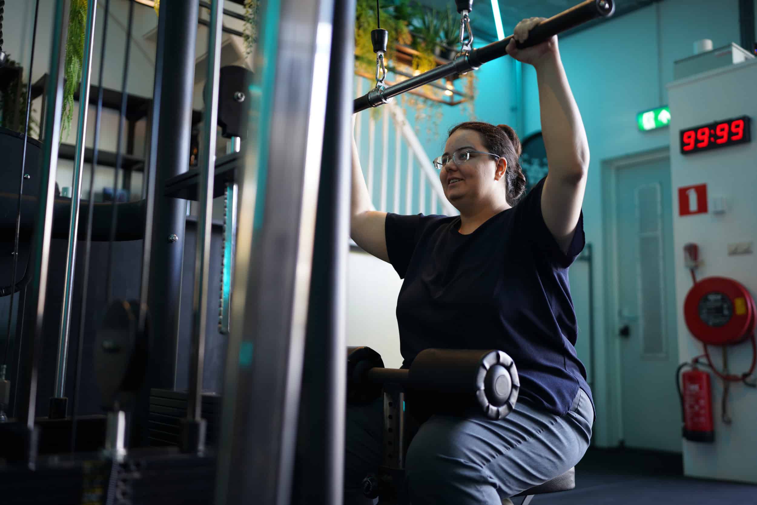 Vrouw traint haar rug met een lat pulldown bij Jouw Krachtstation