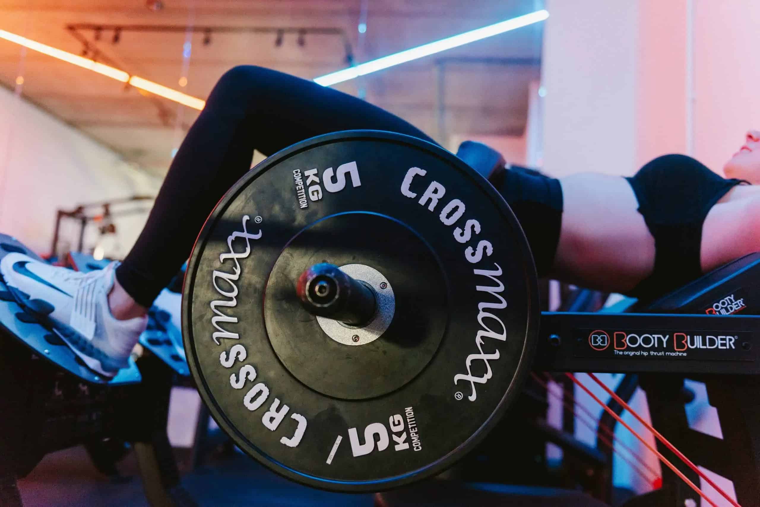 Een vrouw traint haar bilspieren met de hip thrust in de Booty Builder-machine
