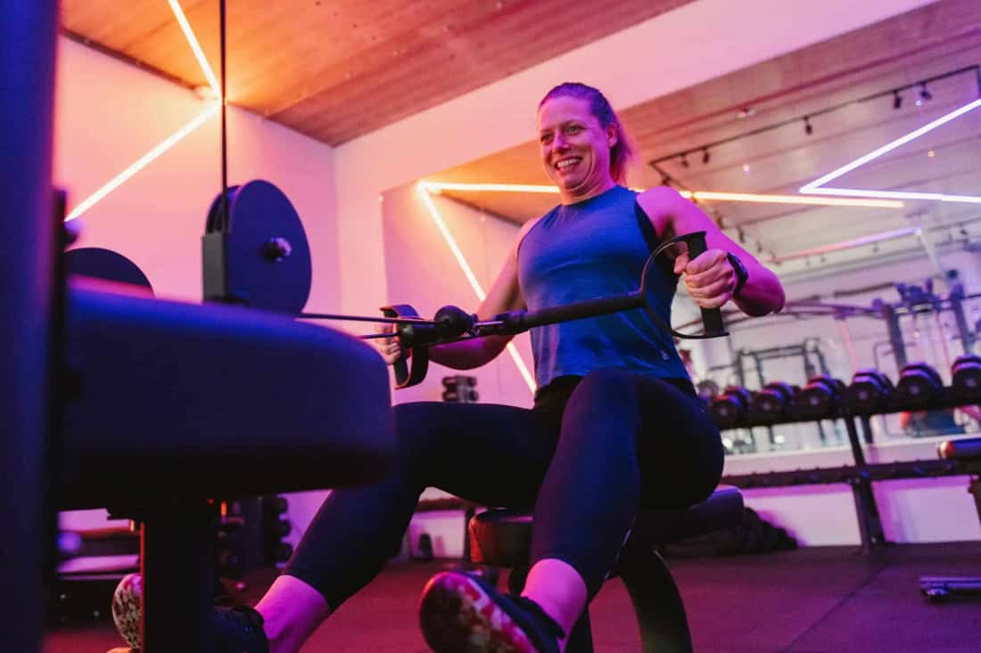 Vrouw doet zelfstandig een zittende kabelroeioefening in de gym