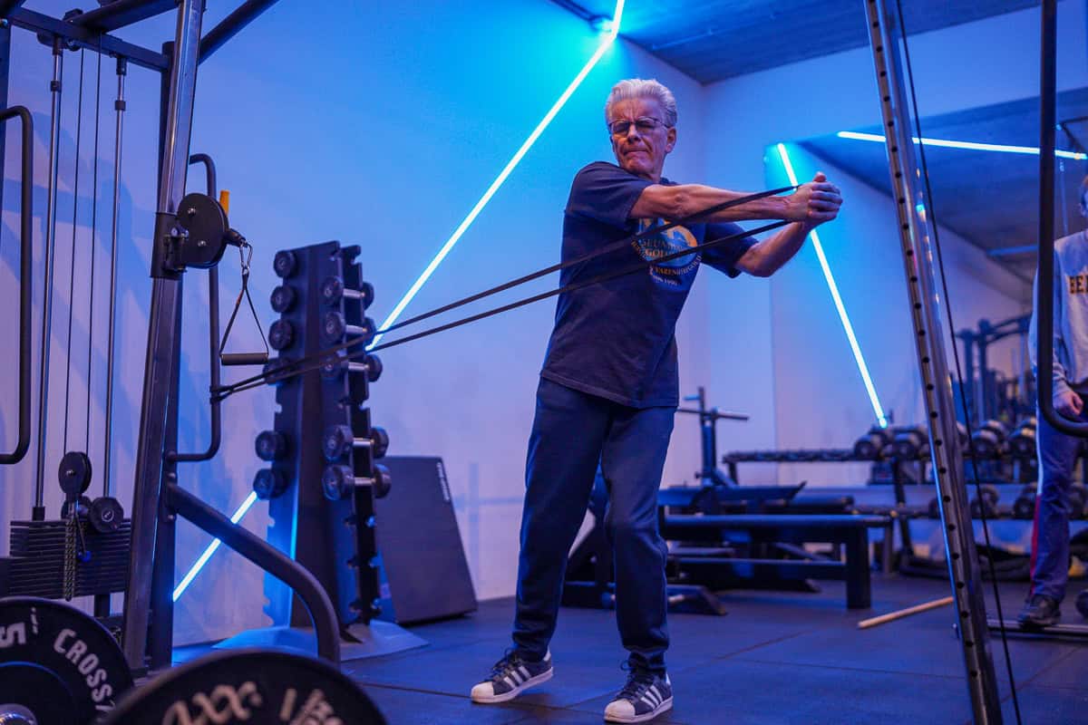 Man traint staand met kabelweerstand in de gym