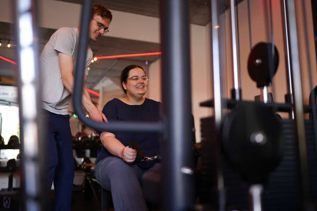 Vrouw doet een seated cable row terwijl een trainer meekijkt