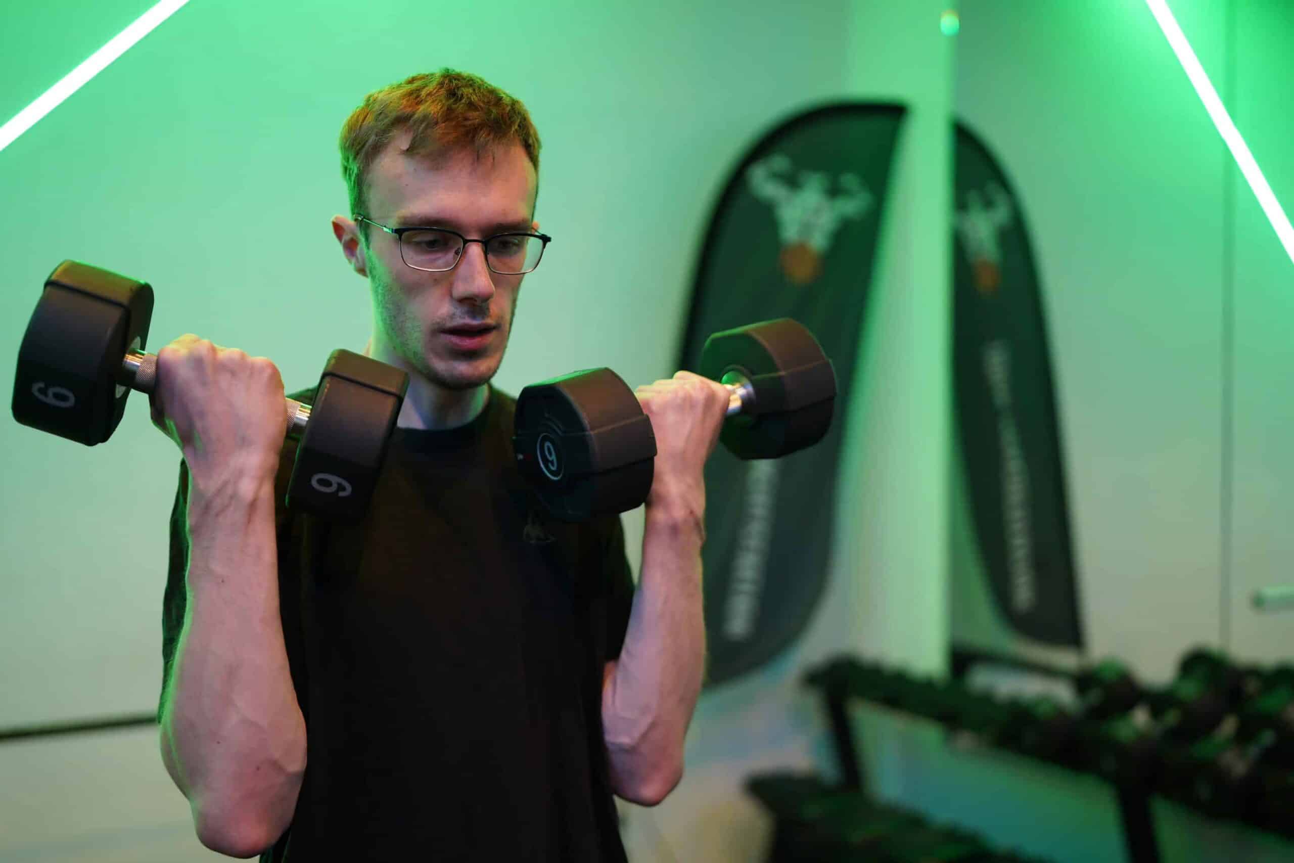 Een man doet een biceps curl met dumbbells in de gym.