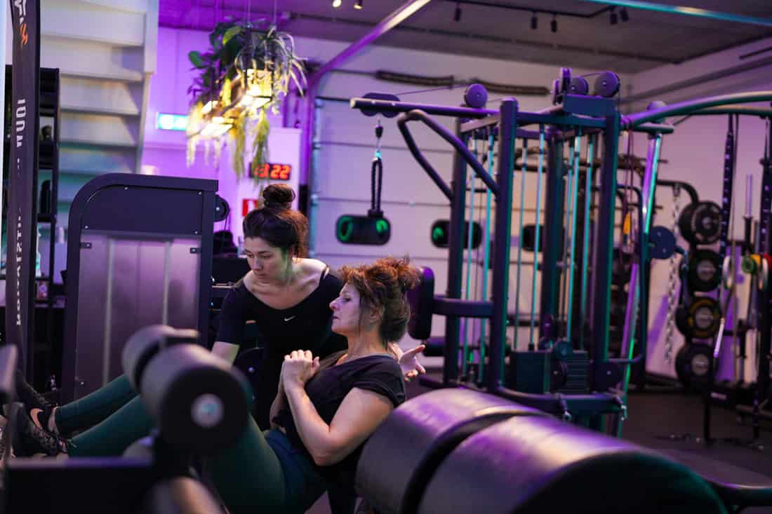 Anna begeleidt een vrouw bij krachttraining in Jouw Krachtstation.