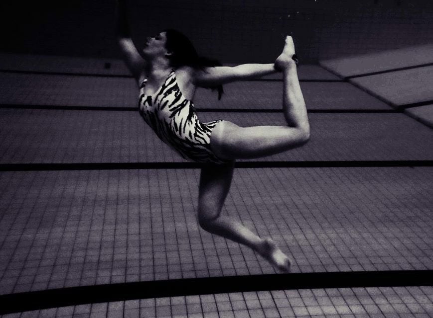 Anna maakt onder water een synchroonzwemhouding.