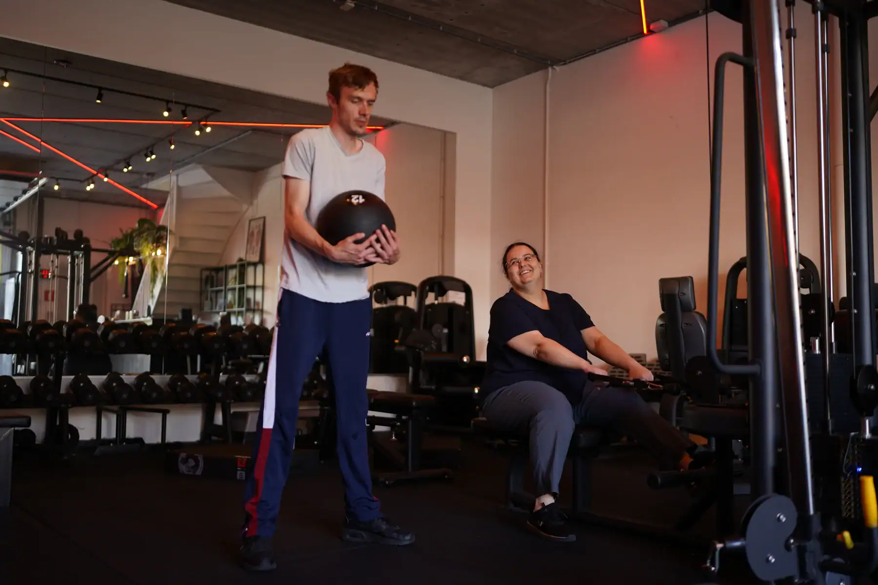 Twee sporters doen ieder een eigen oefening tijdens duo personal training in de privé gym in Bodegraven.